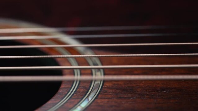 Acoustic guitar strings vibrating. Playing on classic music instrument. Sound waves, strumming chords, sound resonance. Super macro slider footage.