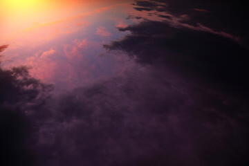 Sunrise, sunset above planet Earth from space, epic storm sky with dark violet pink clouds, orange yellow sun and sunlight. View from space over thunderstorm rain clouds