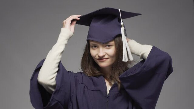 Graduation girl putting on cap. Female student wearing protective face mask. Unsuccessful try.