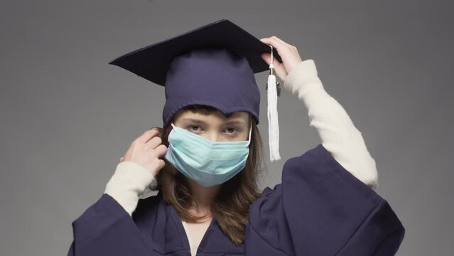 Graduation girl wearing cap and taking off  protective face mask. Female student smiling and throwing hat in the air.