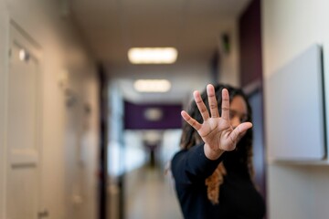 Female adult with her arm held up against a white wall in a confident and determined stance