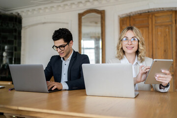 Internet marketing agency two marketers work in the office using laptops and a tablet. A copywriter...