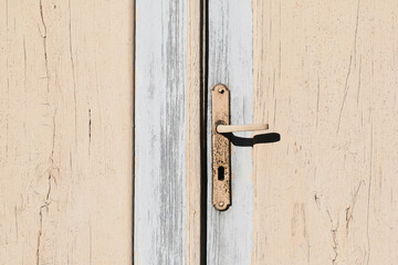 Old wooden door. Closeup rusty door handle. Metal keyhole. Vintage rustic architecture. Empty copy space wood. Paint peel off.