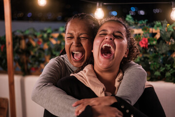 Mother and daughter laughing together and having fun on the terrace of their house. Concept: family, fun, smile