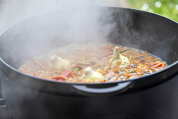 Real Uzbek pilaf in a huge cauldron. Cooking national dishes in Uzbekistan. Rice with meat in a cauldron. Traditional pilaf cooking