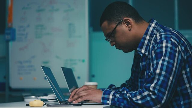 African American IT specialist typing programming code, testing software at work