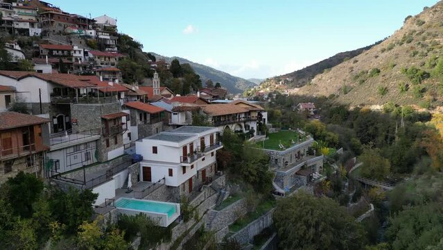 Low angle drone flight over rooftops of steeply built village in mountains of Troodos (Pedoulas), architecture and rural landscape in Cyprus
