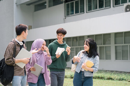 Multi ethnic group of university students walks and talks together outdoors on campus during a break.