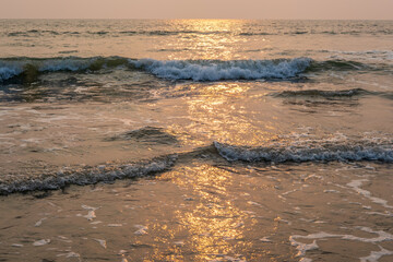 foam of sea or ocean waves against the backdrop of the setting sun
