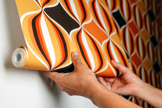 man attaching a geometric wallpaper to a wall