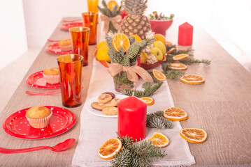 Christmas holiday table decorated with candles, Christmas tree branches, dried oranges, sweets and fruits,selective focus.Cozy house decorated for the holiday with handmade items.Christmas decoration
