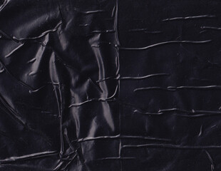 Crumpled black plastic surface background. Creased dark plastic texture. Wrinkly wrapper backdrop. Glossy and shiny polyethylene. - obrazy, fototapety, plakaty