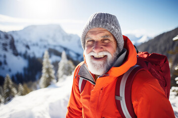Fototapeta na wymiar Elderly man wearing bright orange jacket hiking in winter mountains