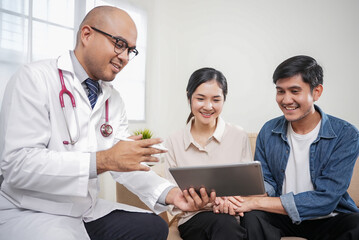 Asian couple discussing infertility problems with a handsome doctor, They feeling happy and holding...