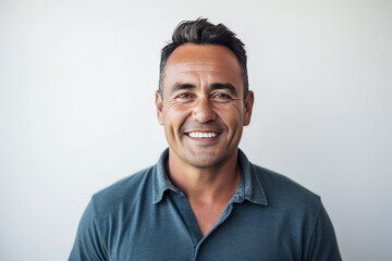 Smiling middle age man in blue shirt isolated against a white wall.