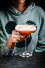 iced latte with foam in a martini glass on a dark background