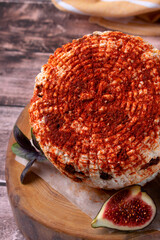 Adyghe cheese sprinkled with smoked paprika and dried tomatoes on the wooden board