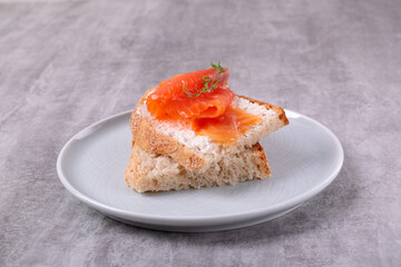 Bruschetta with smoked trout slices and cream cheese on baguette on white plate