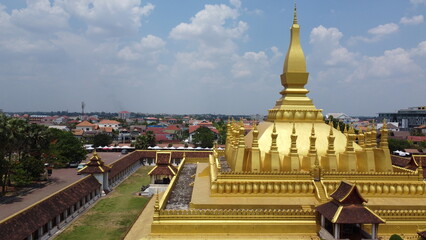 Laos' gilded pagoda shines amidst traditional homes, capturing the essence of local life and heritage