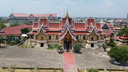 Laos' gilded pagoda shines amidst traditional homes, capturing the essence of local life and heritage