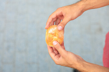 A man's hand holds a round bun, snack and fast food concept. Selective focus on hands with blurred background