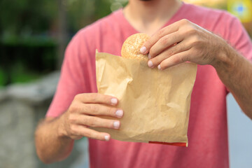 Guy's hand holds mini bread, snack and fast food concept. Selective focus on hands with blurred...
