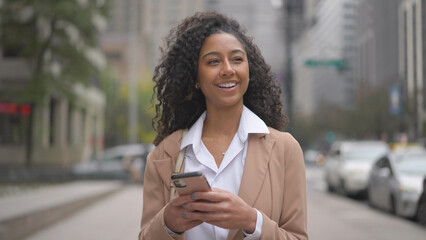 Young black business woman using smart phone on city street