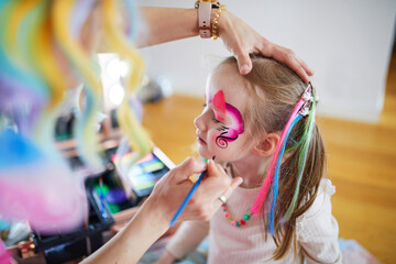 Artist painting little preschooler girl like unicorn on a birthday party. Creative activities for...