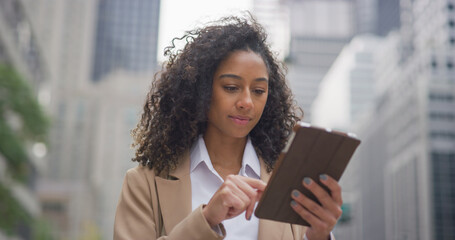 Young black business woman using tablet computer on city street