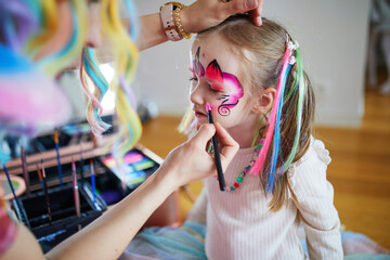 Artist painting little preschooler girl like unicorn on a birthday party. Creative activities for kids - obrazy, fototapety, plakaty