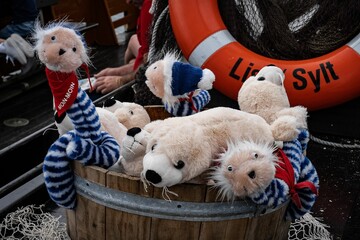 Group of plush toys wearing buoyancy aids in a barrel.