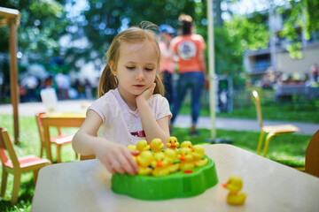 preschooler girl playing board game outdoors