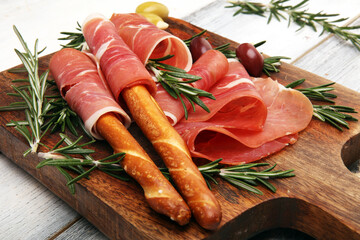 Italian prosciutto crudo or jamon with rosemary. Raw ham appetizer on table