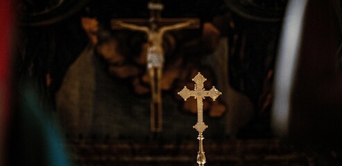 Metal cross stands in a church with a blurred dark background