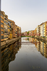 View of Onyar river at Girona in Catalonia with the famous Eiffel bridge in the background and its typical colored houses.