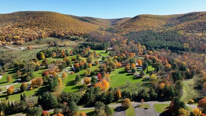 Camping in the great outdoors in nature in campgrounds for RVs and tents on a green pastures below a mountain range in Autumn Fall colors in Ives Run Campground in Pennsylvania countryside - obrazy, fototapety, plakaty