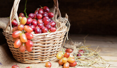 Red grapes, naturally sweet fruit, are placed on a wooden table and arranged in a wooden basket. on the old wooden background
