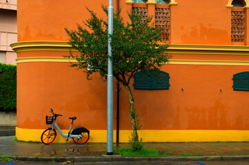 Rental bike is parked on orange background wall in Pisa, Italy. Concept of healthy lifestyle. Colorful city bike for rent. Autumn rainy weather