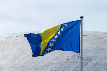 The national flag of Bosnia and Herzegovina   waving in the blue sky