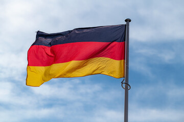 The national flag of Germany waving in the blue sky