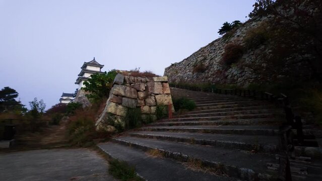 Walking up stairs by stone wall at Akashi Castle on quiet early morning