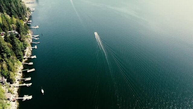 Aerial video of a boat in the sea next to the shore covered with trees