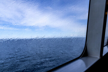 Raindrops on the window overlooking the sea. Background with sea and sky on a rainy day.