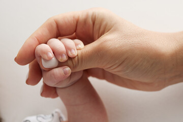 Parents' hands hold the fingers of a newborn baby. The hand of a mother and father close-up holds the fist of a newborn baby. Family health and medical care. Professional photo on white background