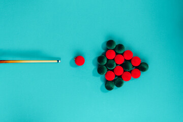 Creative Christmas tree made from red and green velvet Christmas balls and billiard cue on a turquoise background like pool table. Minimal Christmas or New Year concept. top view, copy space