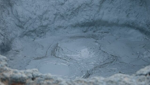 Bubbling gray mud puddles in Hverir, Iceland. Geothermal area, strong sulfur smell. Toxic gases and unstable ground. Heat causes the water to evaporate and mix with mud.