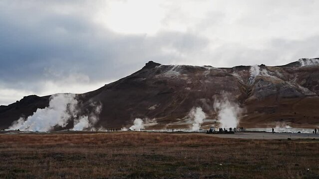 Timelapse of Námafjall Geothermal Area. Tourists stroll among steaming fumaroles and boiling mud pots. Panorama of suggestive volcanic landscape. Geothermal steam and boiling springs. 4k video.