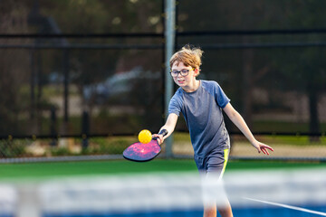 Boy playing pickleball on court - Powered by Adobe