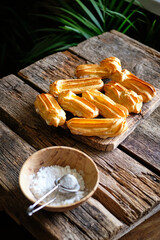 Homemade Eclairs with powdered sugar. Side view, wooden background.