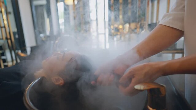 Hairdresser in beauty salon massage head customer and hair care in procedure of steaming water steam. Customer feeling relax while hairdresser massaging head at beauty barber shop